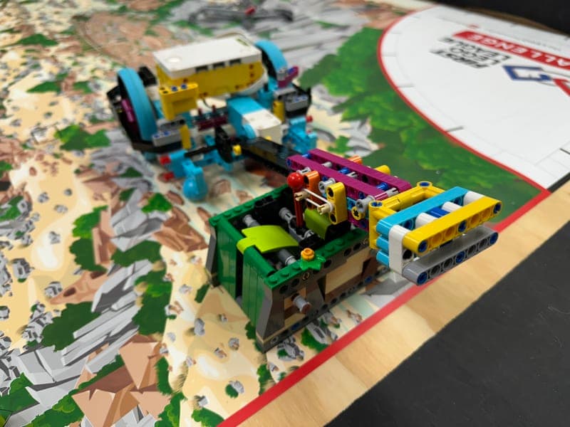 A LEGO robot smashing the top of a LEGO construction on a table